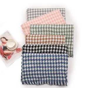 Stack of multi-colored houndstooth scarves with fringe details in a lifestyle setting.