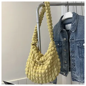 Close-up detail of a yellow puffy bubble textured cloud shoulder bag hanging on a metal rack