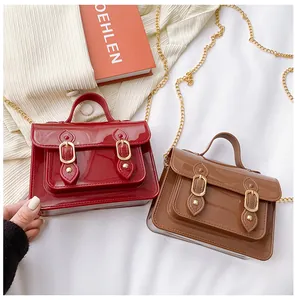 Detailed macro view of red and brown glossy jelly Cambridge bags with gold chain straps
