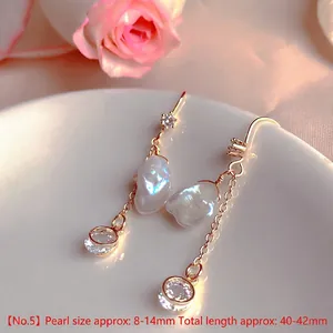 Detail of baroque pearl drop earrings with sparkling zircon accents and gold chain