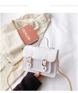 Close-up view of a white glossy PVC mini Cambridge bag with gold chain strap and buckles