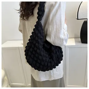 Back view of a woman wearing a black textured bubble hobo bag with a light blazer