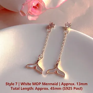 Detail view of mermaid tail drop earrings with shimmering white shell and cubic zirconia stones.
