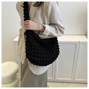 Close-up of black bubble textured cloud bag worn with a beige blazer for daily commute