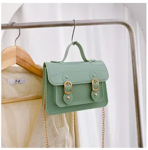 Mint green jelly Cambridge bag with gold buckles hanging on a rack as a stylish accessory