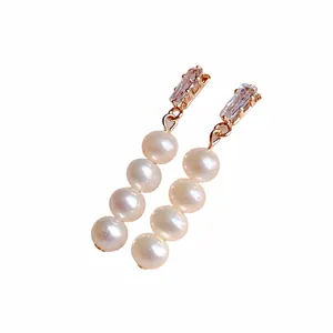 Detailed view of elegant freshwater pearl drop earrings with zircon studs on white plate