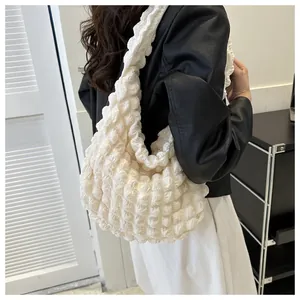 Detailed view of cream white bubble textured cloud underarm bag on a model shoulder