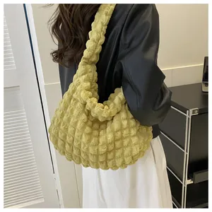 Detailed side view of the yellow bubble textured cloud shoulder bag worn by a fashion model.