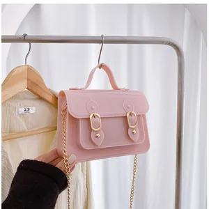 Close-up of a stylish pink jelly Cambridge bag hanging on a white rack for summer.