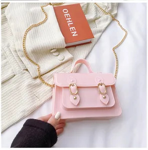 Detail showing the pink jelly satchel bag with a gold chain and buckle on a cozy background.