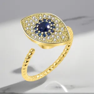 Detail of gold evil eye rotating ring with blue and white cubic zirconia stones.