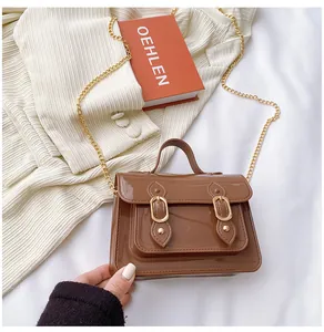 Close-up of a brown jelly Cambridge bag with a gold chain strap and decorative buckles.