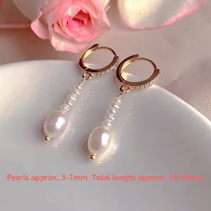 Close-up of freshwater pearl drop earrings with zircon-studded hoops and size labels