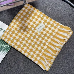 Close-up of yellow and white houndstooth scarf with fringe and label detail