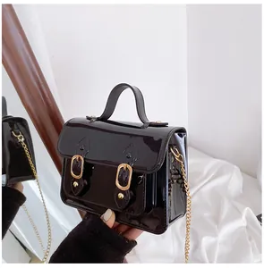 Detail view of a black glossy jelly Cambridge satchel featuring elegant gold buckles