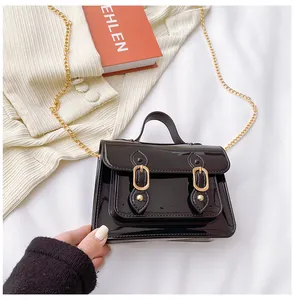 Close-up of a high-gloss black jelly Cambridge bag featuring a gold chain strap and buckles