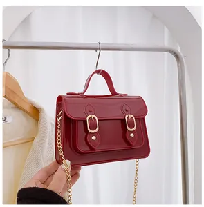 Detailed macro view of dark red glossy jelly Cambridge bag with elegant gold chain strap