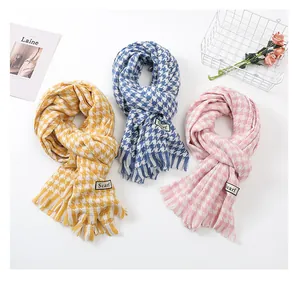 Detailed view of three colorful houndstooth scarves with fringe and 'Scarf' labels