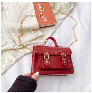 Close-up of a red jelly Cambridge bag with gold chain strap and magnetic buckle