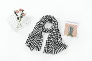 Detailed view of a classic black and white houndstooth scarf with fringe details