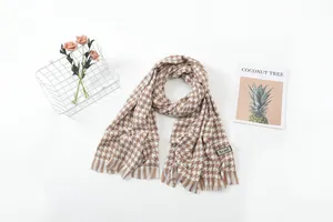 Detailed view of brown and white houndstooth scarf with fringe and soft texture.