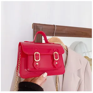 Detailed shot of a red jelly Cambridge bag with shiny gold buckle and chain strap