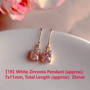 Macro detail of rectangular white zircon drop earrings displayed on white ceramic plate