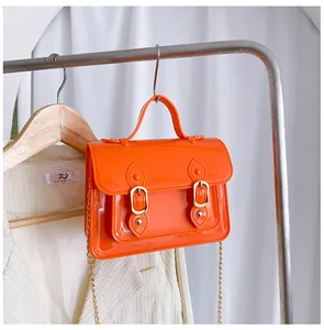 Detailed view of an orange jelly Cambridge bag hanging on a rack with chain strap.