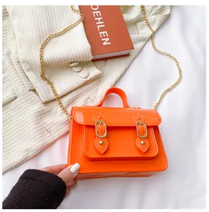Close-up of bright orange jelly Cambridge satchel bag with elegant gold chain strap.
