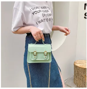 Close-up of mint green jelly Cambridge bag worn by a model in casual style
