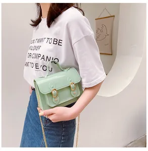 Close-up of a mint green jelly Cambridge bag with gold chain strap worn by model.