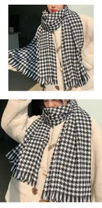 Detailed view of a soft black and white houndstooth scarf with elegant fringe edges