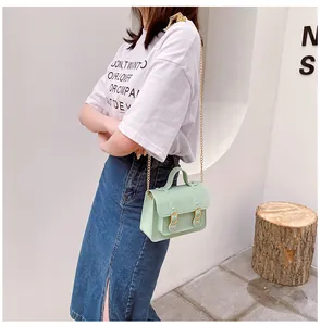 Lifestyle view of a mint green jelly Cambridge bag with decorative gold chain strap and handle