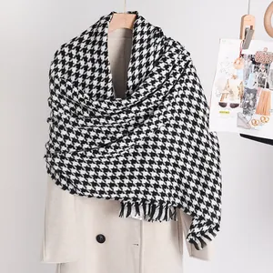Detailed macro view of a classic black and white houndstooth winter scarf on a beige coat.