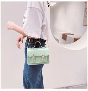 Stylish mint green jelly Cambridge crossbody bag with gold chain strap on model.