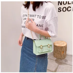 Detail of a light green jelly Cambridge bag with golden buckles worn by a model