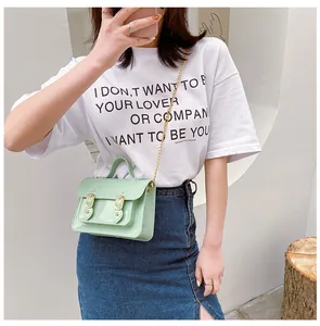 Stylish mint green jelly Cambridge satchel bag with gold chain strap shown on model