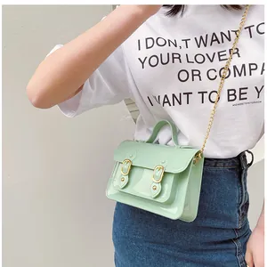 Close-up detail of a mint green jelly Cambridge bag featuring gold chain strap on a model