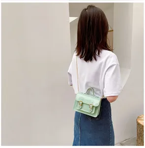 Detail view of a stylish mint green jelly Cambridge crossbody bag worn by a model.