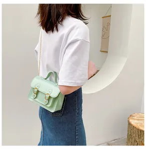 Side view of model wearing a mint green jelly Cambridge bag with gold buckles