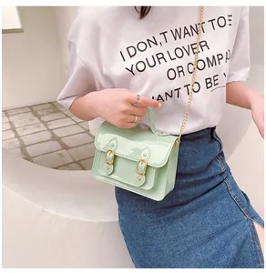 Mint green glossy jelly Cambridge bag with gold chain strap being carried by a model