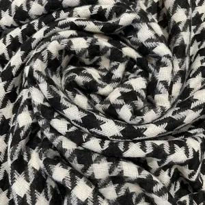 Macro texture of black and white houndstooth scarf with elegant spiral fold pattern.