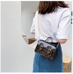 Stylish glossy black jelly Cambridge crossbody bag featuring a gold chain strap detail