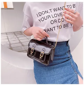 Stylish black jelly Cambridge satchel bag with gold chain strap carried by a model.