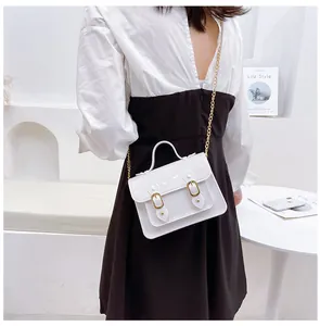 Close-up detail of a glossy white jelly Cambridge bag featuring elegant golden buckles