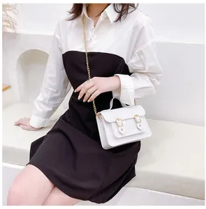 White jelly Cambridge satchel bag with gold chain shown on a model sitting down