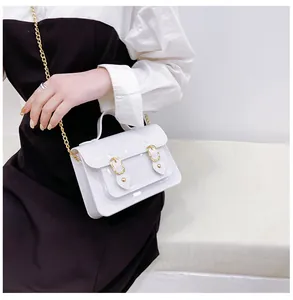 Detailed view of white jelly Cambridge bag held by a model with gold chain strap