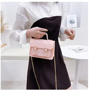 Detailed view of a trendy pink jelly Cambridge satchel bag held by a person in a white top