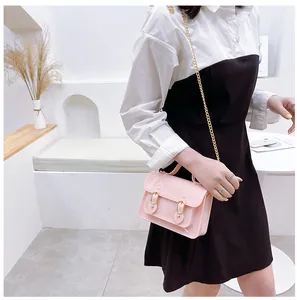 Detailed shot of a pink jelly Cambridge crossbody bag on a model in a minimalist room.