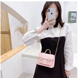Pink mini jelly Cambridge bag with gold chain strap worn by model in a white outfit.